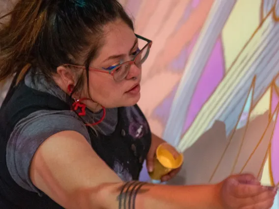 Jessica Gonzales painting the undercoating for mural, "Dandelion"