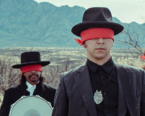 Wide shot of the Tucson-based band named XIXA as they stand in the desert
