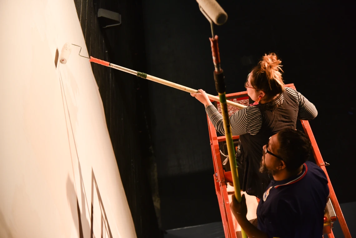 Photo of two artists using brushes to paint a mural