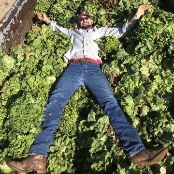 Portrait of Duke Pauli laying down on a bed of green lettuce